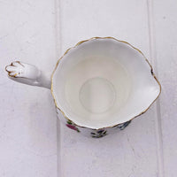 Elegant porcelain creamer with floral design, gold trim, and scalloped edge for vintage home décor