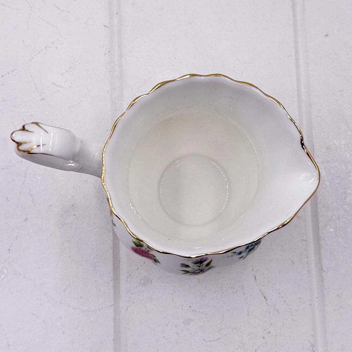 Elegant porcelain creamer with floral design, gold trim, and scalloped edge for vintage home décor