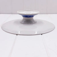 White ceramic pedestal dish with blue floral band, elegant home décor accent on white surface