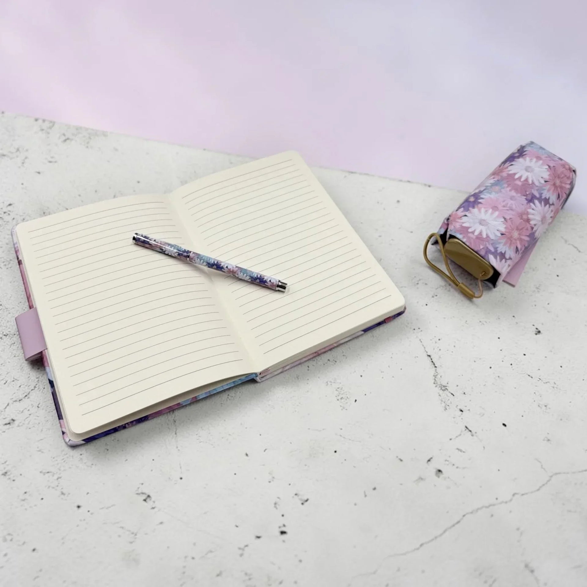 Floral notebook with lined pages, matching pen, and pouch on marble surface, perfect for home décor and journaling.