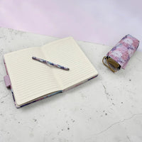 Floral notebook with lined pages, matching pen, and pouch on marble surface, perfect for home décor and journaling.