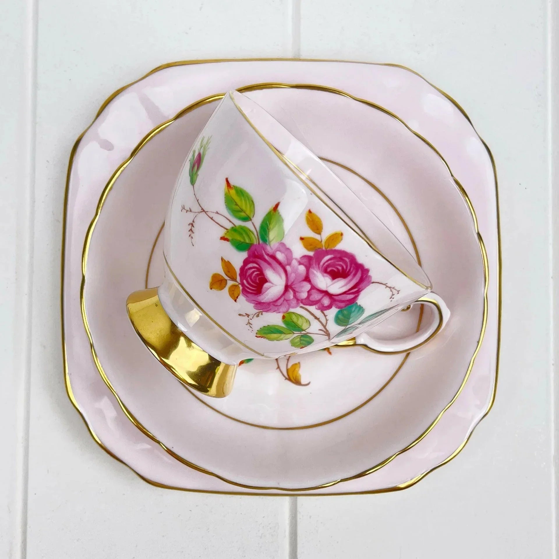 Elegant pink tea cup and saucer with gold trim and rose floral design, perfect for home decor