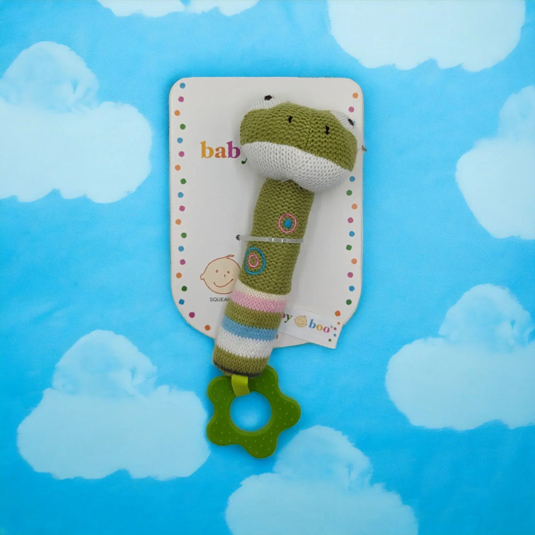 Knitted green frog baby rattle with teether, soft toy for infants, cloud background