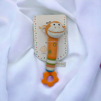 Knitted monkey baby rattle with teether, colorful stripes, and squeaker on soft white fabric