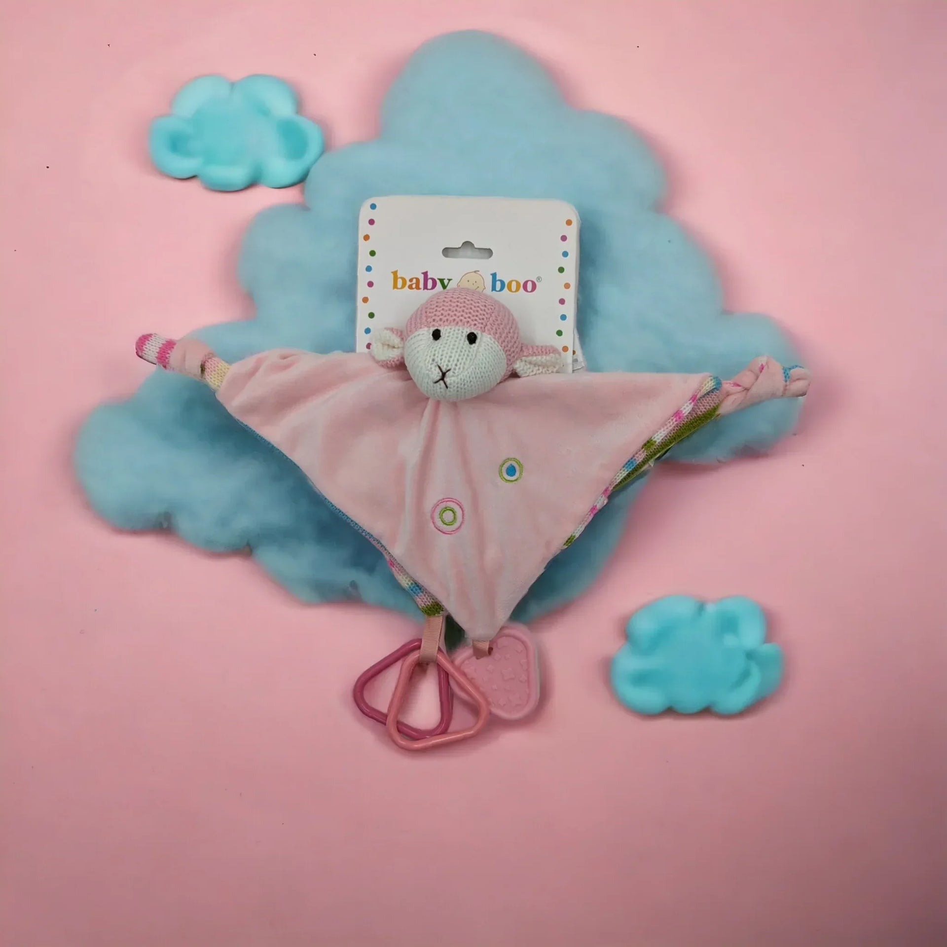 Pink knitted monkey lovey blanket with teether rings, soft baby comforter on cloud backdrop