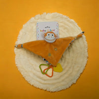 Orange monkey baby comforter with teether rings on fluffy white mat, perfect for infant soothing and play