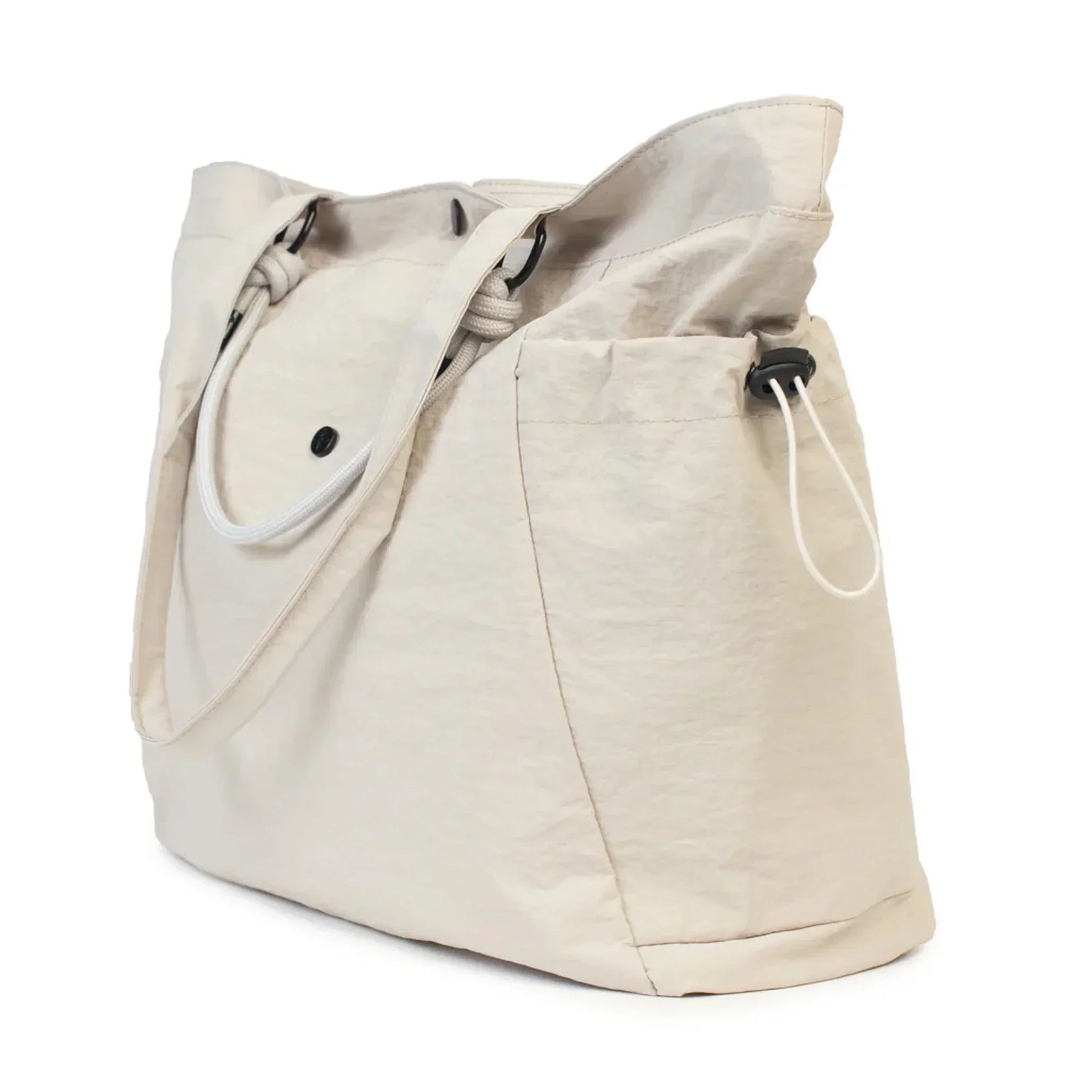 Beige canvas tote bag with drawstring closure and side pockets, ideal for everyday use or beach outings.