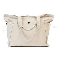 Beige canvas tote bag with side pockets and drawstring closure, perfect for everyday use or shopping.