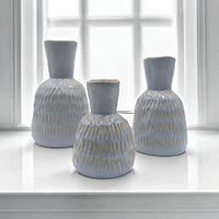 Set of three light blue textured ceramic vases on white windowsill, modern home decor accents