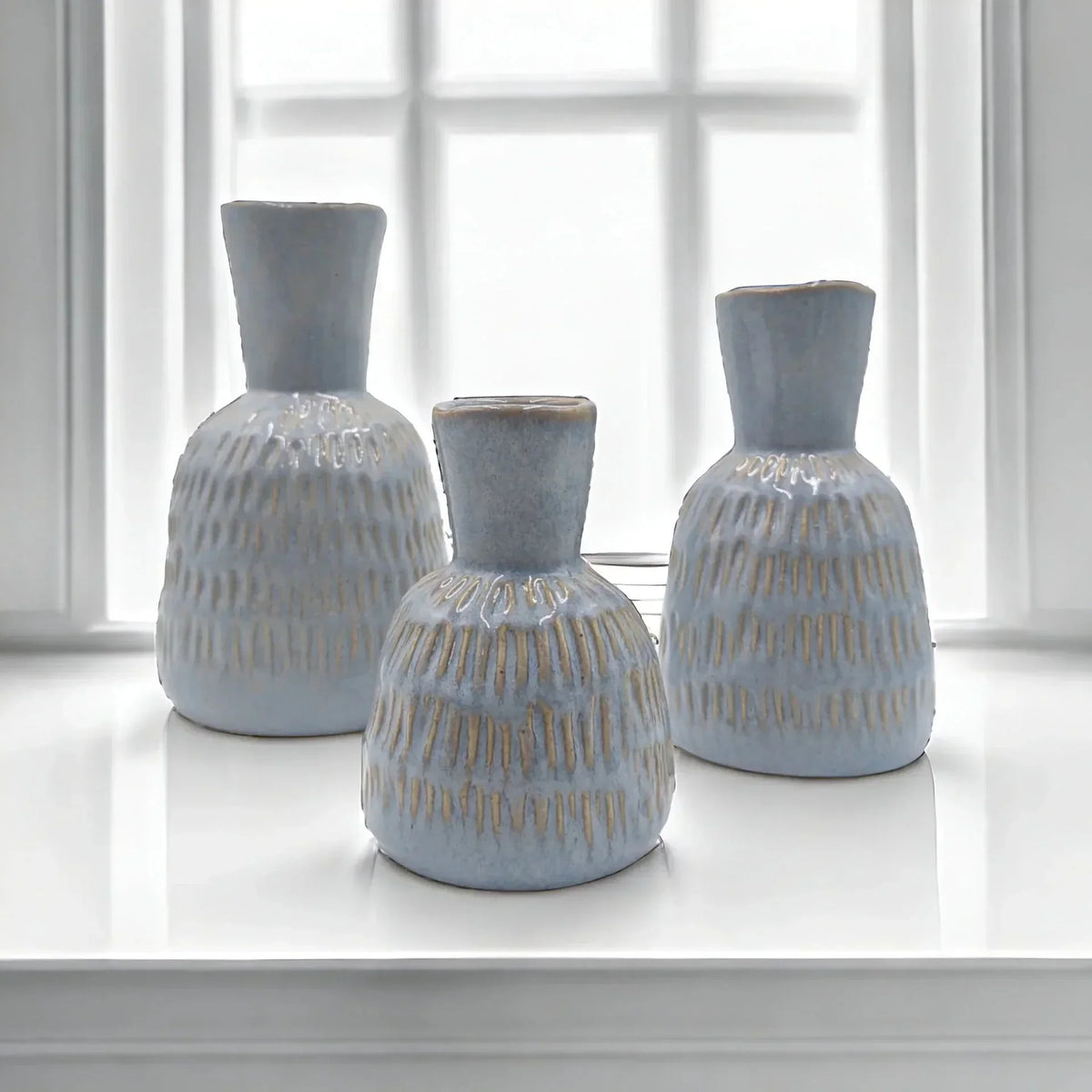 Set of three light blue textured ceramic vases with gold accents, perfect for modern home décor styling.