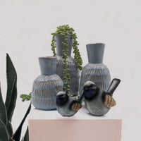Blue ceramic vases with textured glaze, decorative bird figurines, and trailing succulent for home décor
