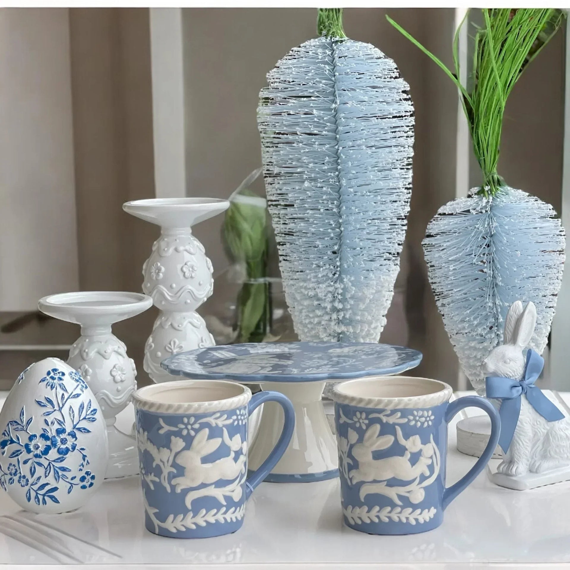 Blue and white ceramic mugs with bunny designs, decorative eggs, and Easter-themed home décor accents