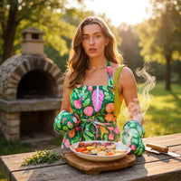 Woman in floral apron holding steaming grilled dish outdoors near stone oven