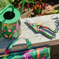 Colorful vegetable-print garden tools: watering can, pruners, and tote on rustic wood