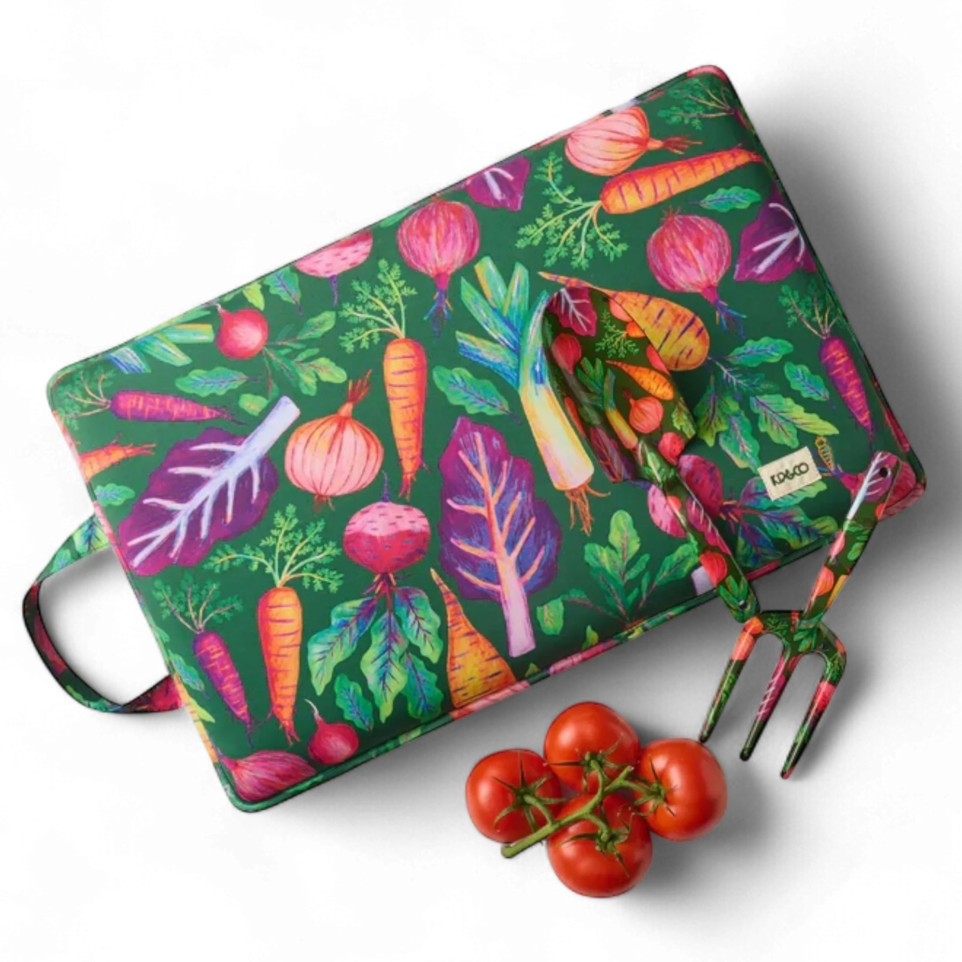 Colorful vegetable-patterned cutting board with matching fork, fresh tomatoes nearby, perfect for kitchen decor