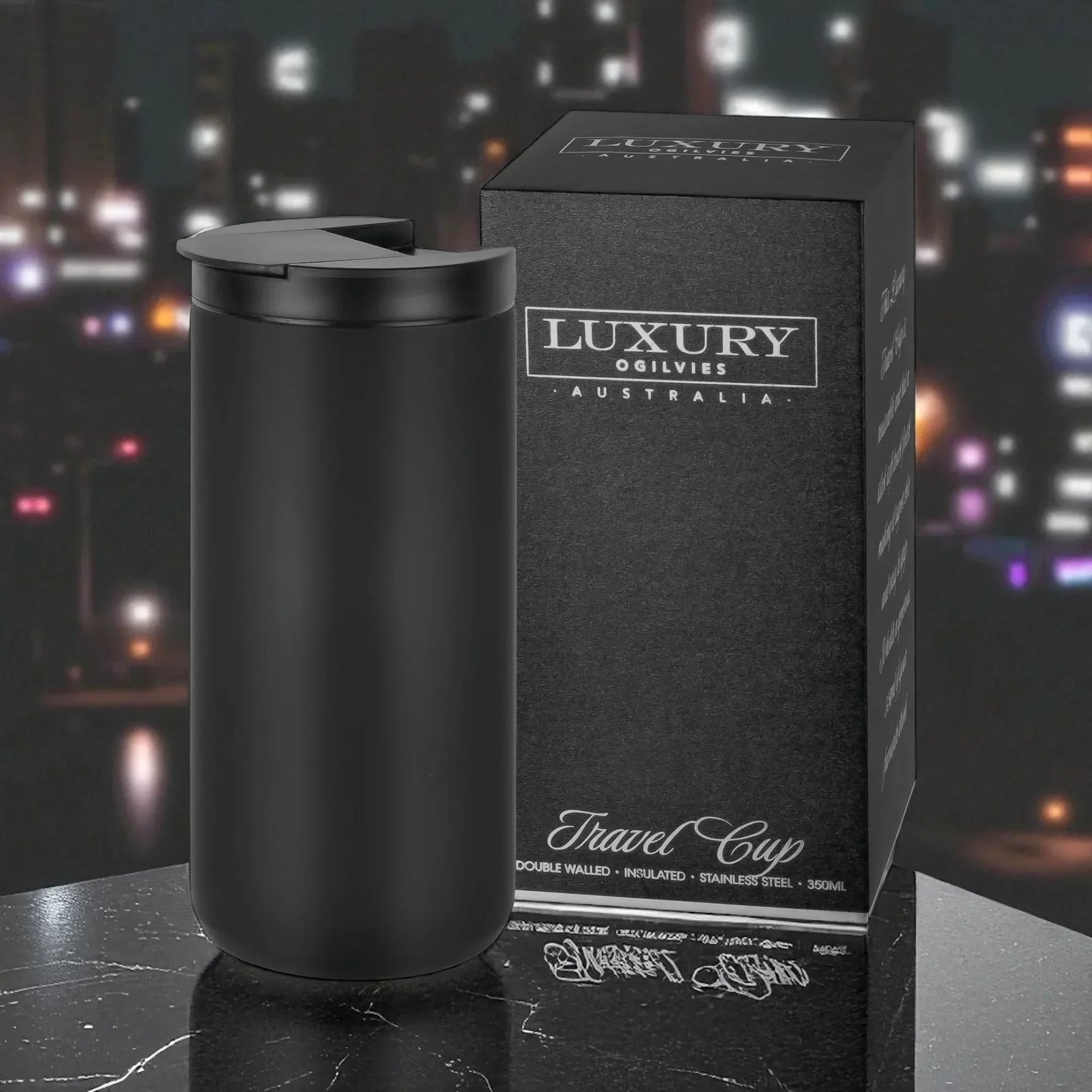 Black insulated travel mug with lid, stainless steel, 350ml, next to luxury packaging on marble surface