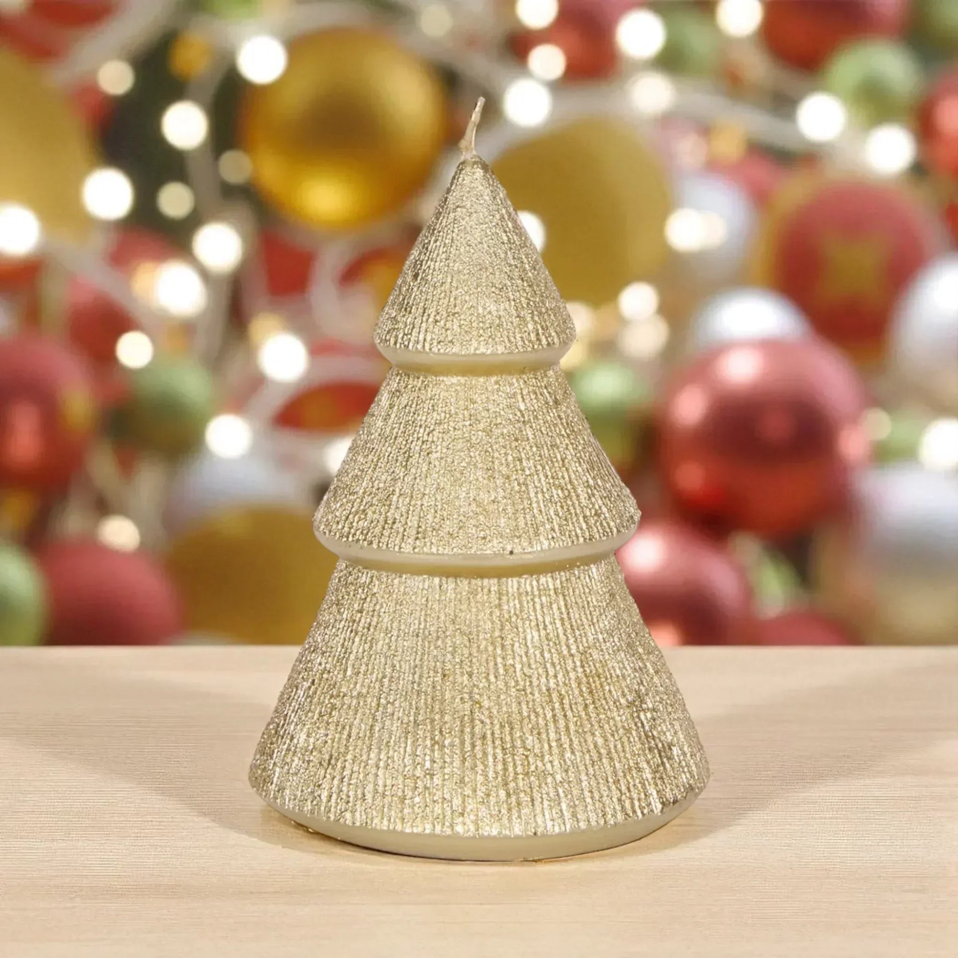 Glittery gold Christmas tree candle for festive home décor with holiday ornaments background