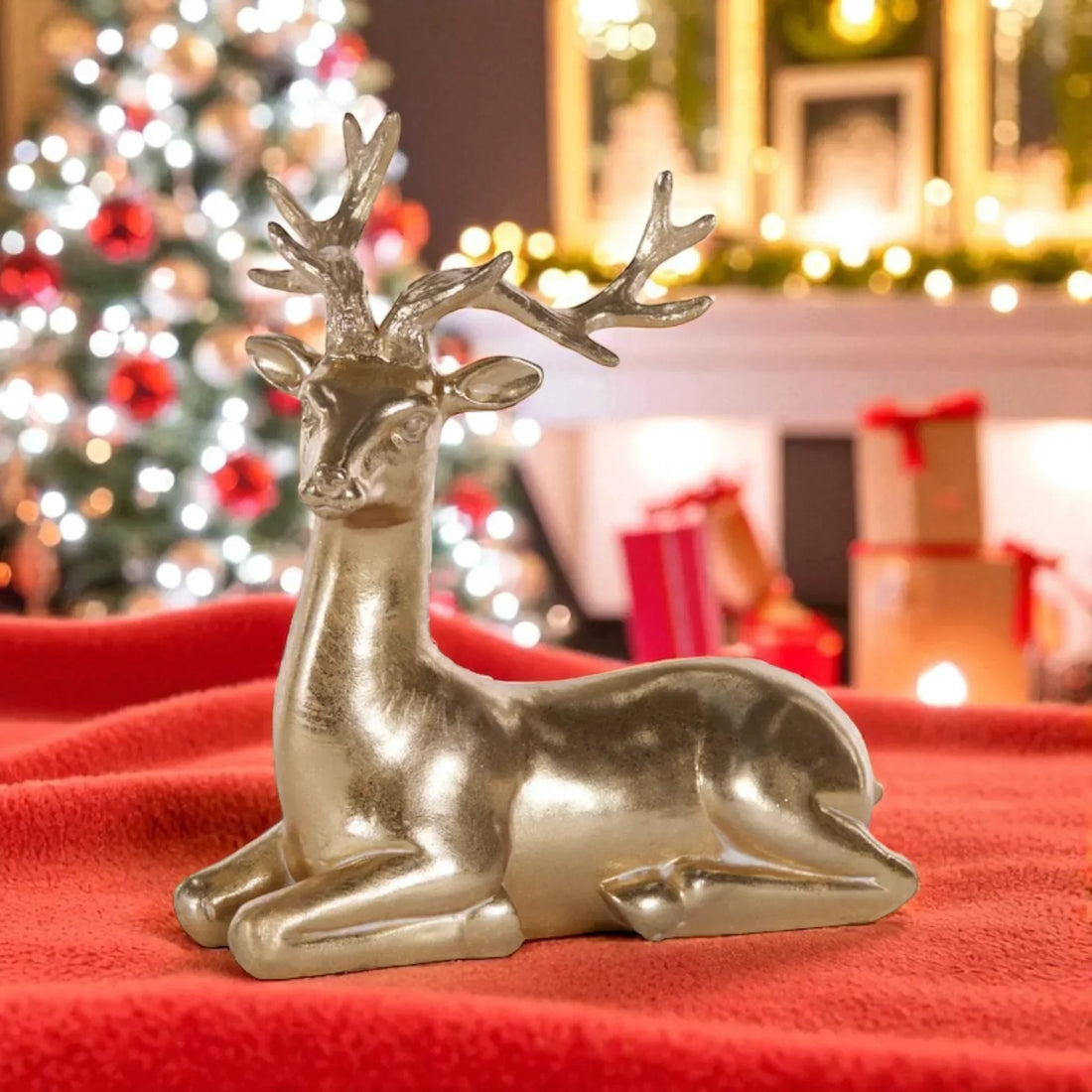 Gold lying deer figurine for Christmas home décor, festive holiday decoration with red blanket and tree background