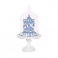 Blue and white decorative cake under glass dome on ornate pedestal, elegant home décor accent piece