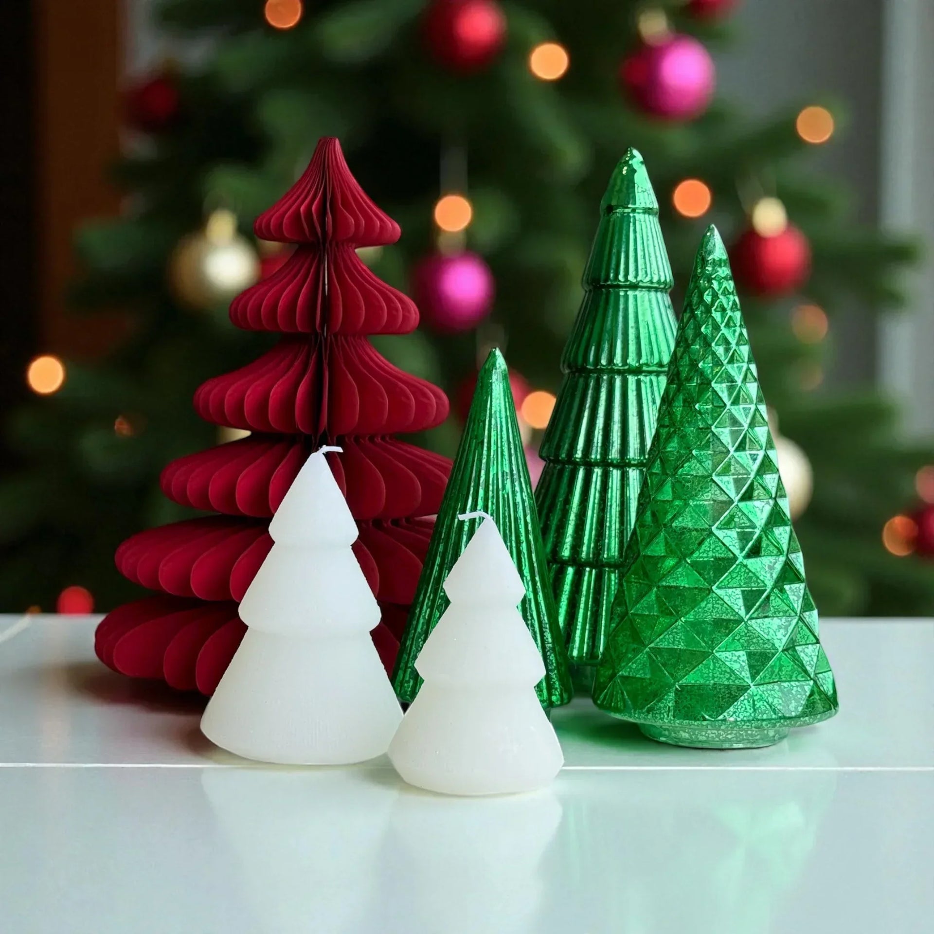 Red, green, and white Christmas tree candles with festive ornaments in background