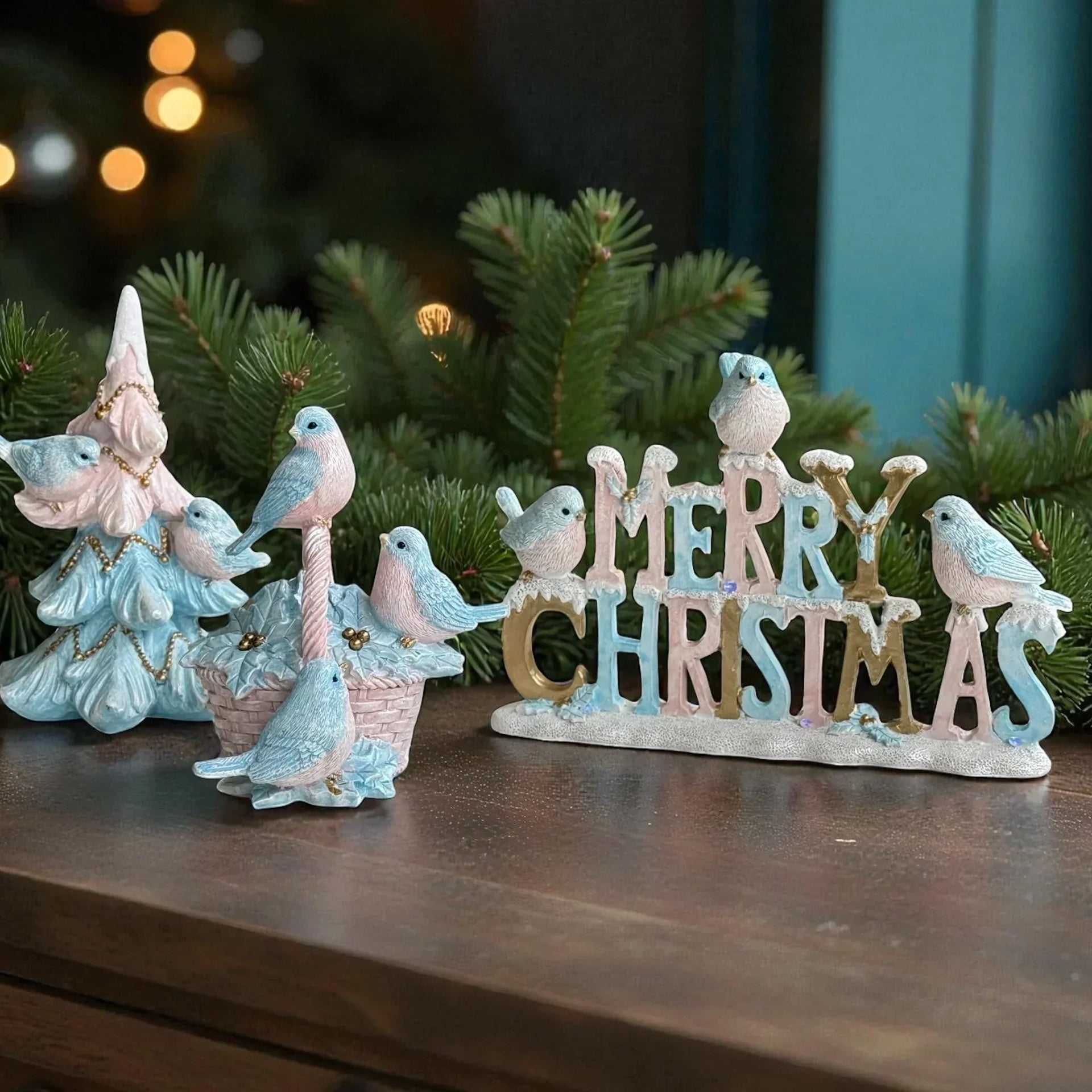 Pastel blue and pink Christmas decor with birds and 'Merry Christmas' sign on wooden surface