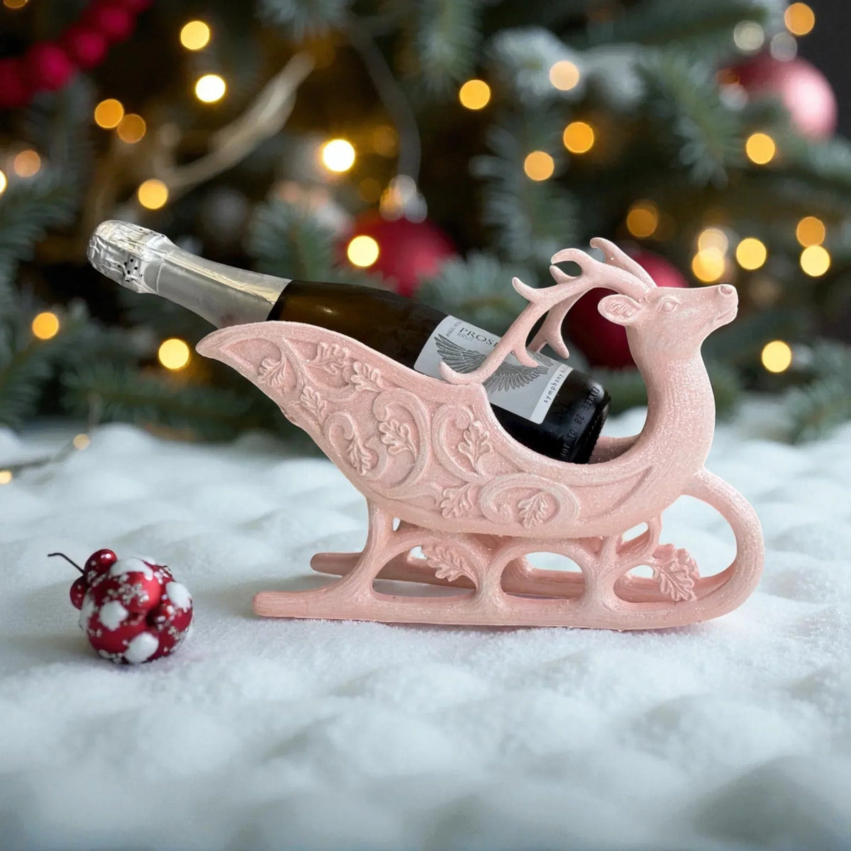 Pink glitter reindeer sleigh wine bottle holder for Christmas decor, festive table centerpiece with snow and ornaments