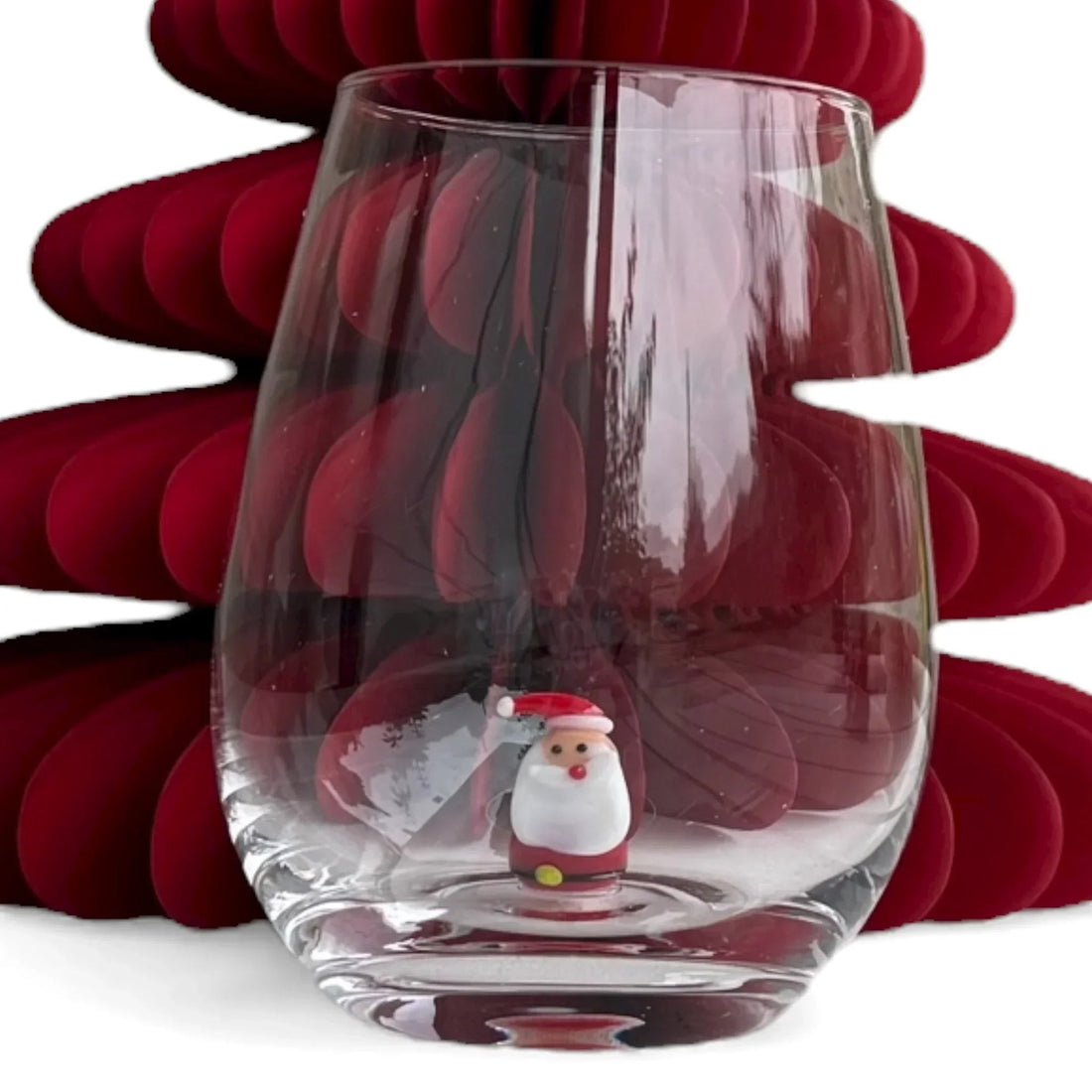 Festive wine glass with Santa figurine, red Christmas tree backdrop, holiday home decor