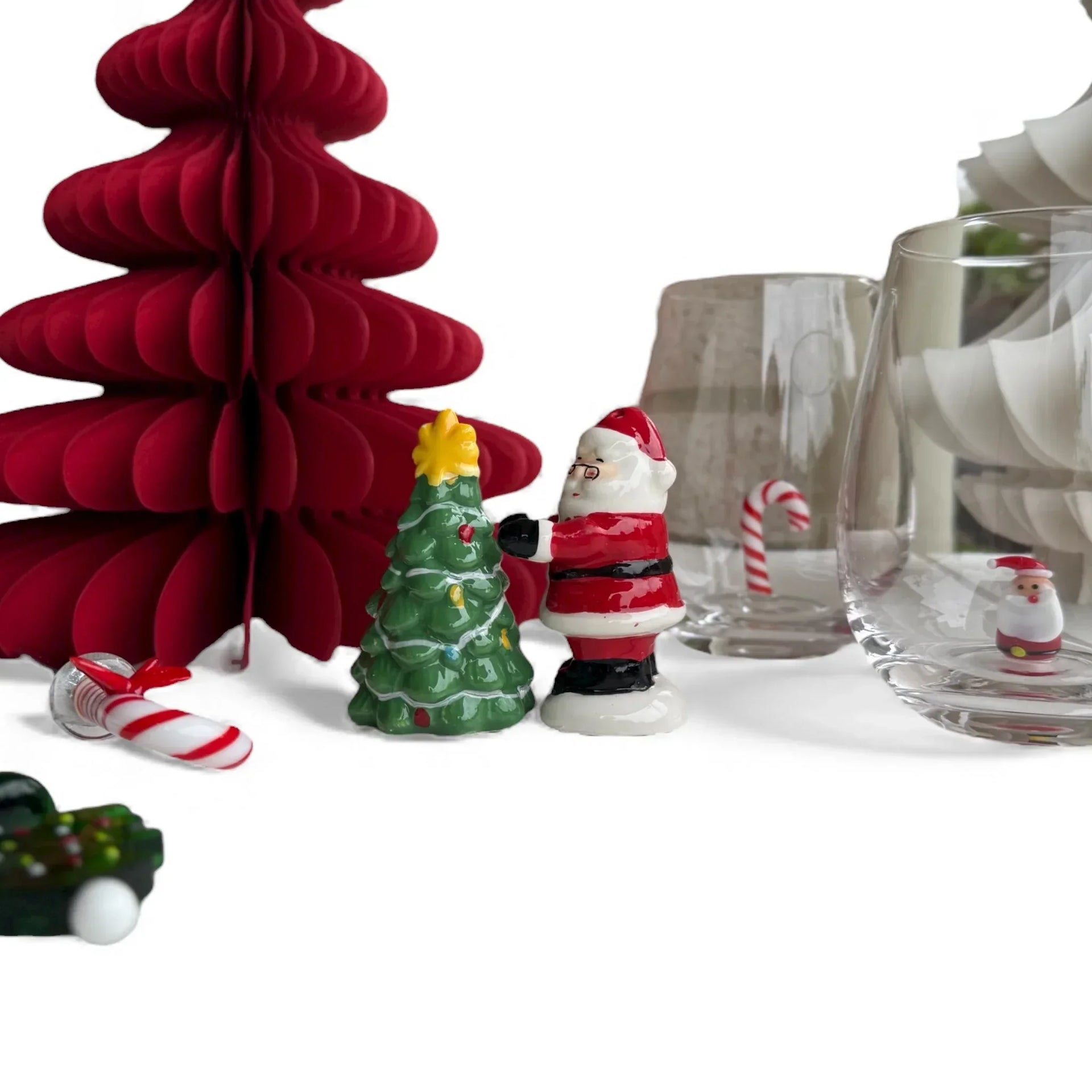 Ceramic Santa figurine beside green Christmas tree with red paper tree and candy canes