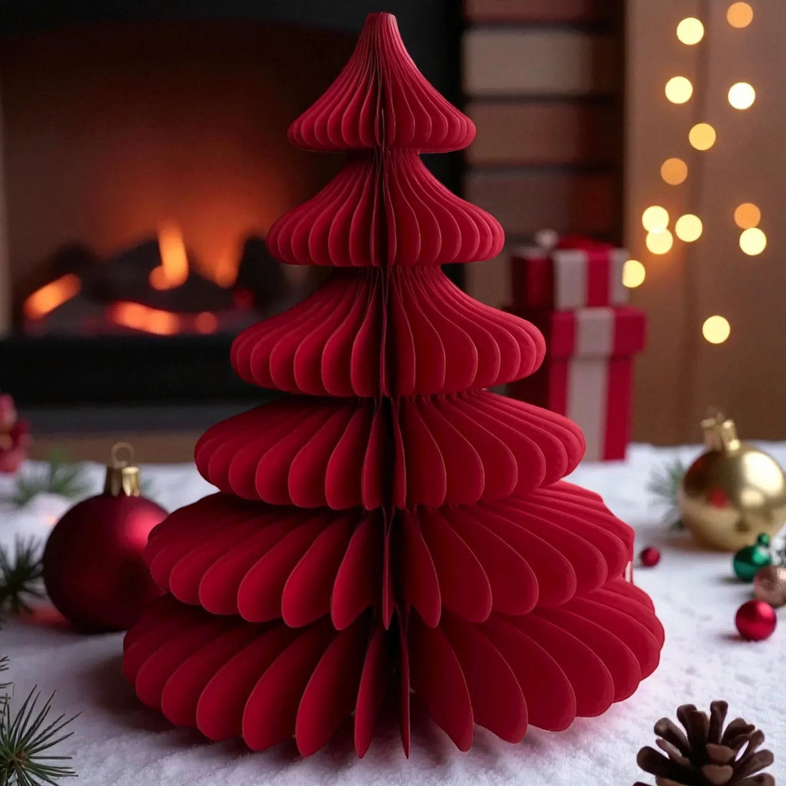 Red paper Christmas tree decoration with festive ornaments, pinecones, and fireplace backdrop