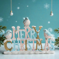 Merry Christmas sign with pastel birds, snow-dusted letters, and festive holiday decor for home tabletop display