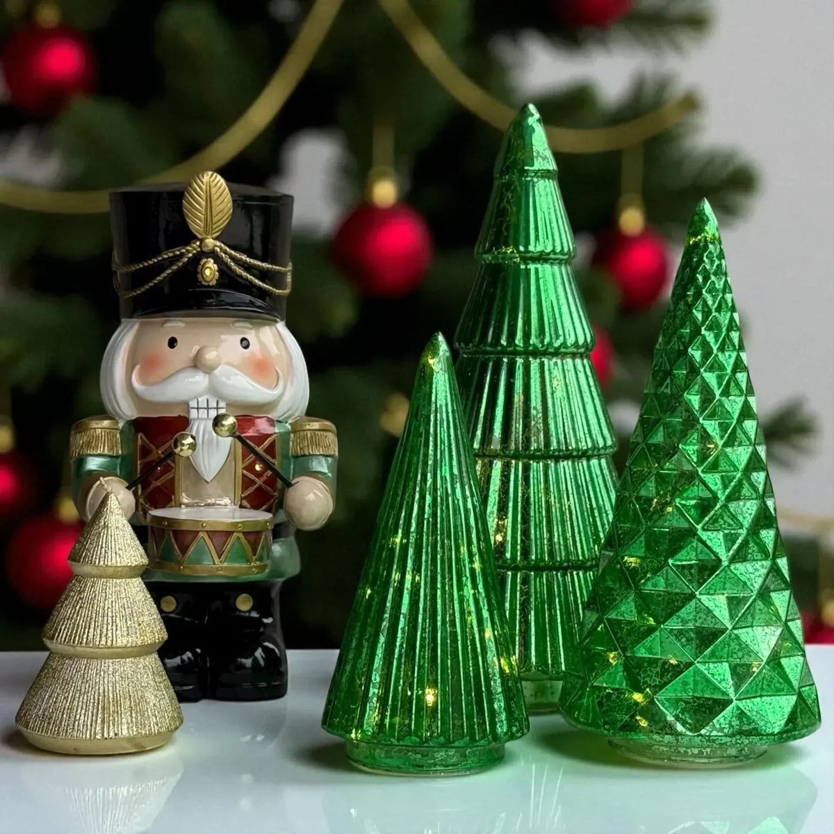 Nutcracker figurine with green and gold Christmas tree decorations, festive holiday home décor