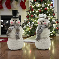 Charming snowman decorations with scarves and hats, perfect for Christmas home décor near a lit tree.