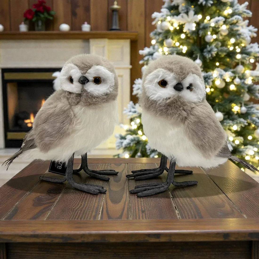 Fluffy grey and white owl figurines on wooden table, festive Christmas tree background, home décor accent