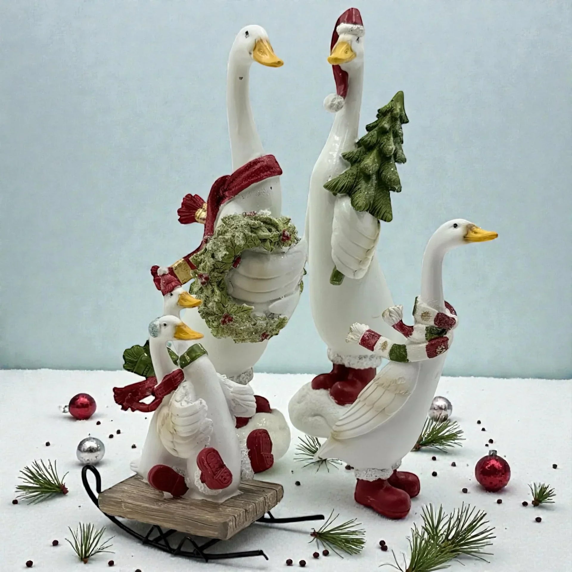Festive white goose figurines with scarves, wreath, and Christmas tree, perfect for holiday home décor