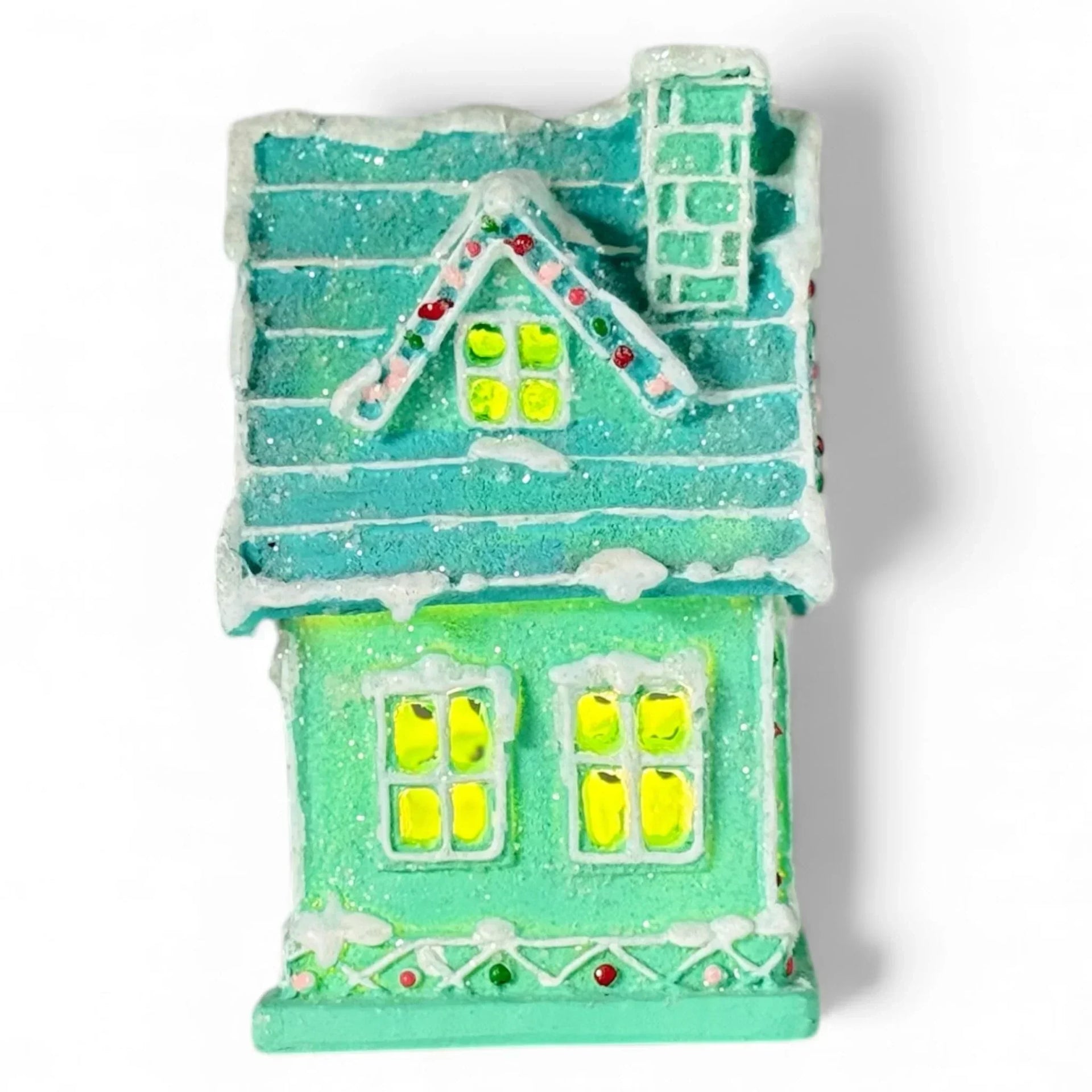 Miniature teal Christmas house with glowing windows, snow-dusted roof, and festive lights for holiday home décor