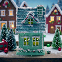Teal glitter gingerbread house with snowy roof, festive windows, and holiday ornaments for Christmas décor