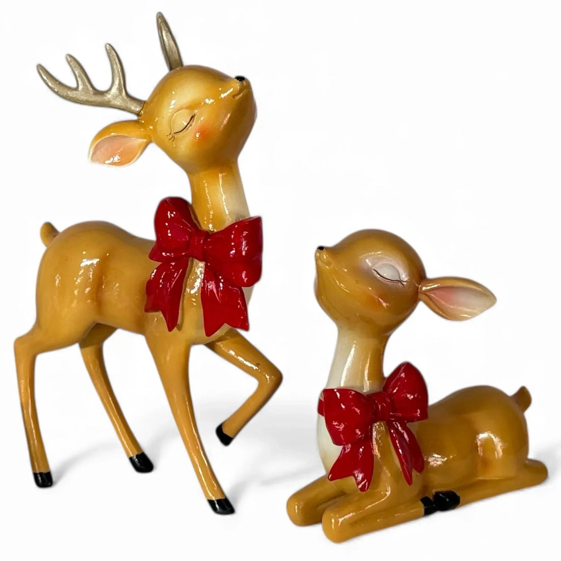Charming deer figurines with red bows, perfect for festive home décor and holiday displays