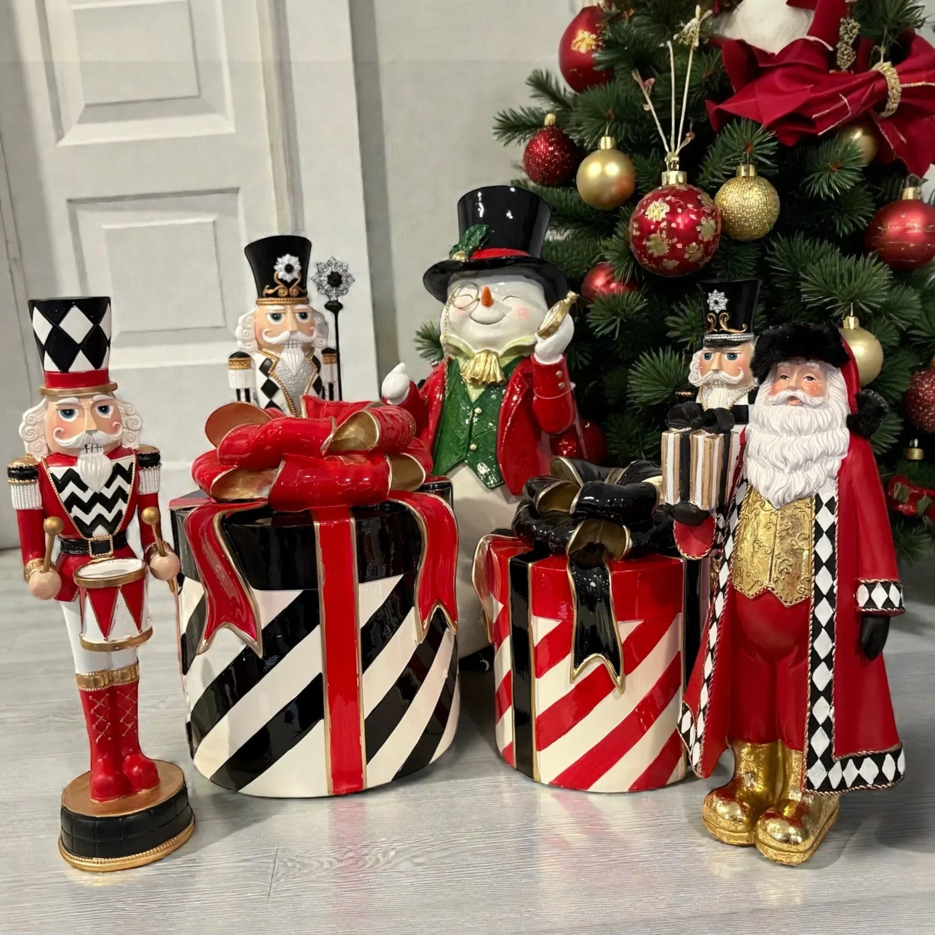 Festive Christmas decor featuring nutcrackers, Santa, snowman, and striped gift boxes near a decorated tree