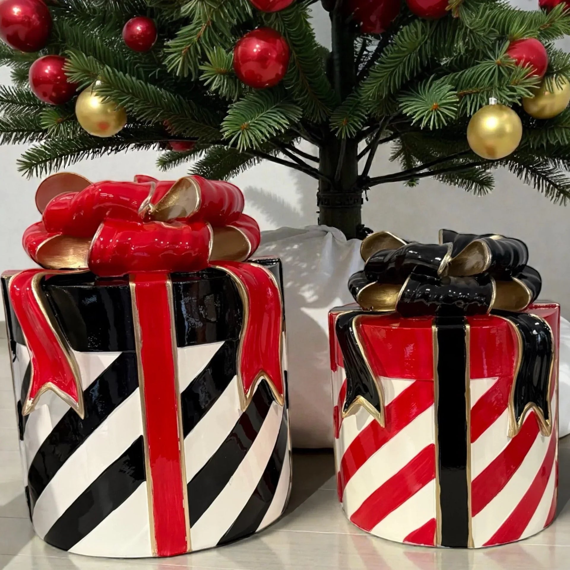 Ceramic gift box decor with red, black, white stripes and bows under Christmas tree