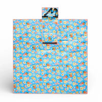 Blue picnic blanket with fruit & flower print, pink trim, and carry strap for outdoor use