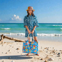 Woman on beach wearing striped robe & hat, holding tropical print tote bag, seaside summer style