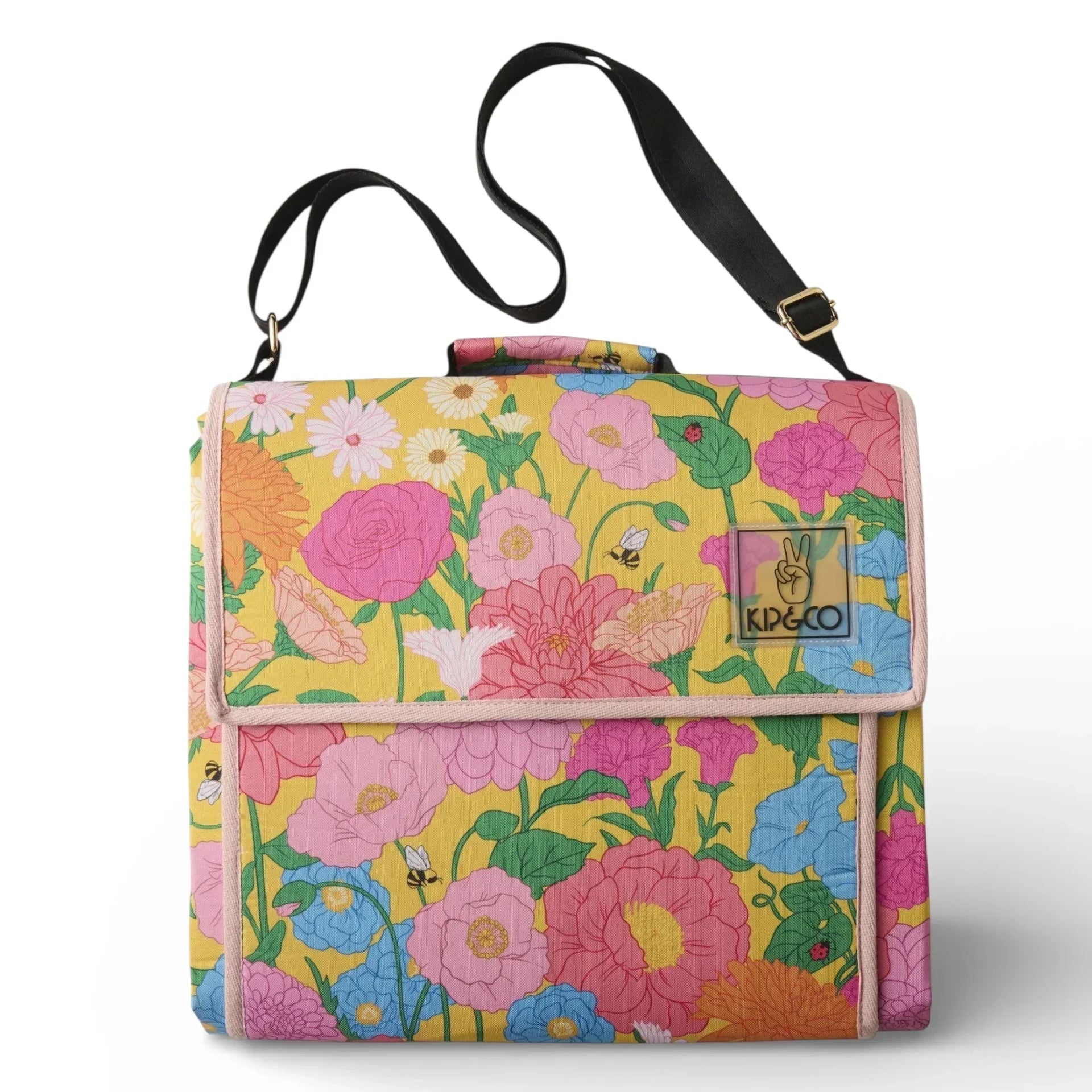 Vibrant floral picnic blanket with pink, blue, and yellow blooms, bees, ladybugs, and adjustable black strap for outdoor use.