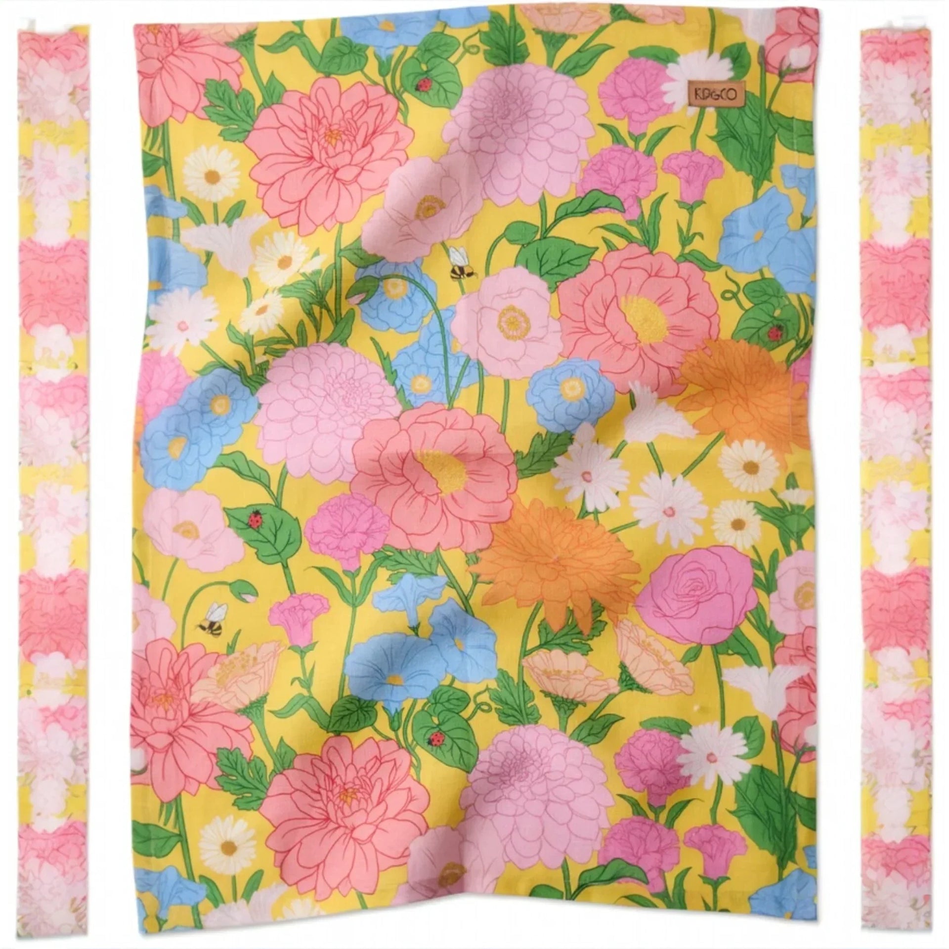 Vibrant floral tea towel with pink, blue, and yellow blooms on sunny yellow background, perfect for kitchen décor