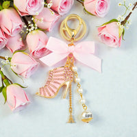 Pink high heel keychain with rhinestones, pearls, and Eiffel Tower charm, surrounded by roses