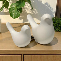 White ceramic bird sculptures for modern home décor, styled on wooden shelf with green plants