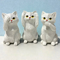 Three white ceramic cat figurines in see-no-evil, hear-no-evil, speak-no-evil poses for home décor