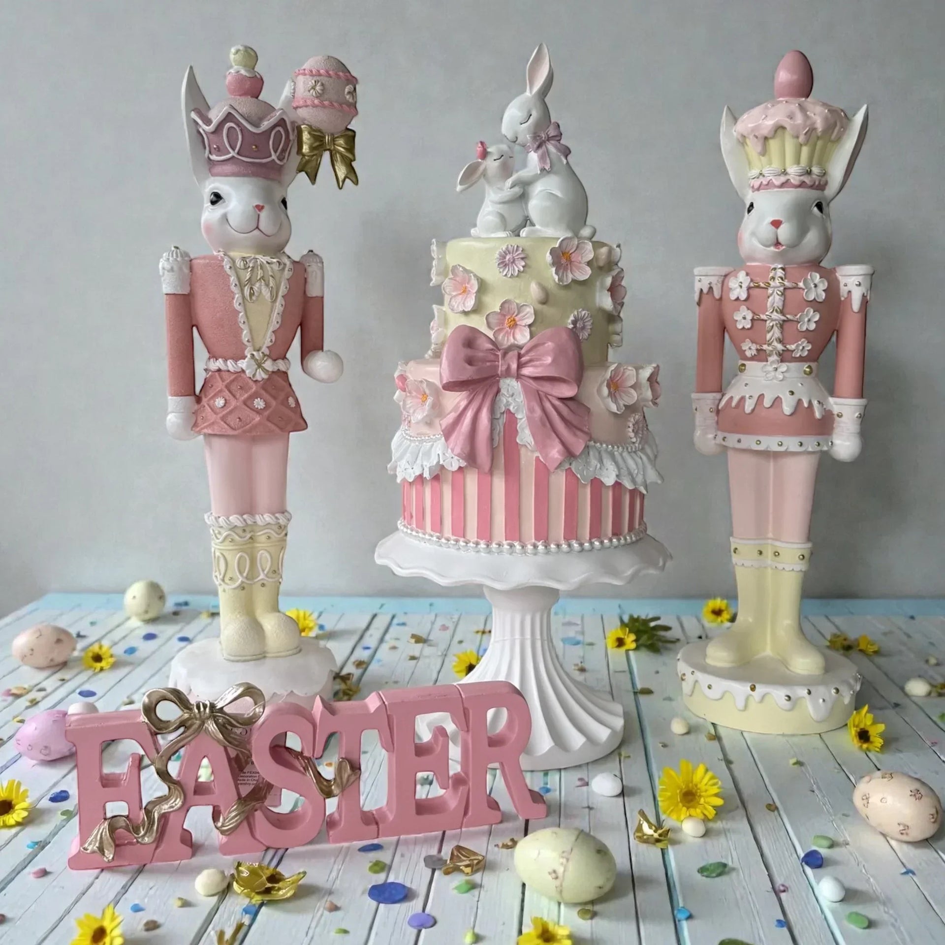 Pink Easter bunny nutcrackers with floral cake, pastel eggs, and 'EASTER' sign for spring home décor