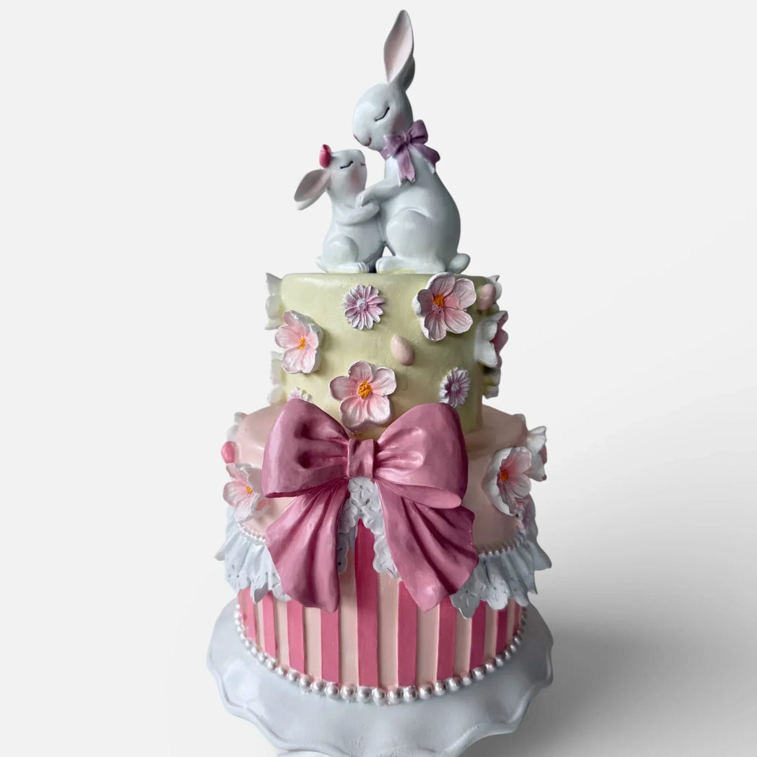 Charming two-tier cake decor with pink bow, floral details, and bunny figurines for home décor