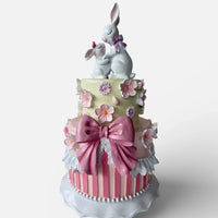 Charming two-tier cake decor with pink bow, floral details, and bunny figurines for home décor