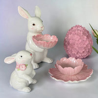 White ceramic bunny figurines with pink floral accents, decorative bowls, and egg-shaped home decor